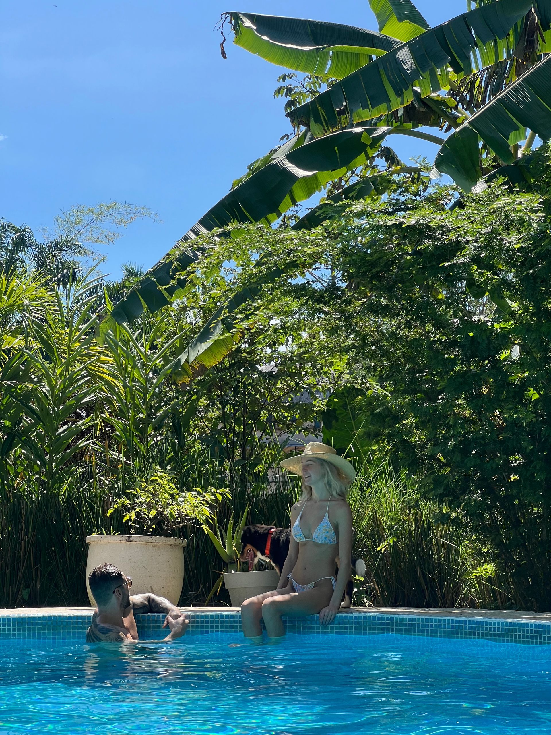 A man and a woman are sitting on the edge of a swimming pool.