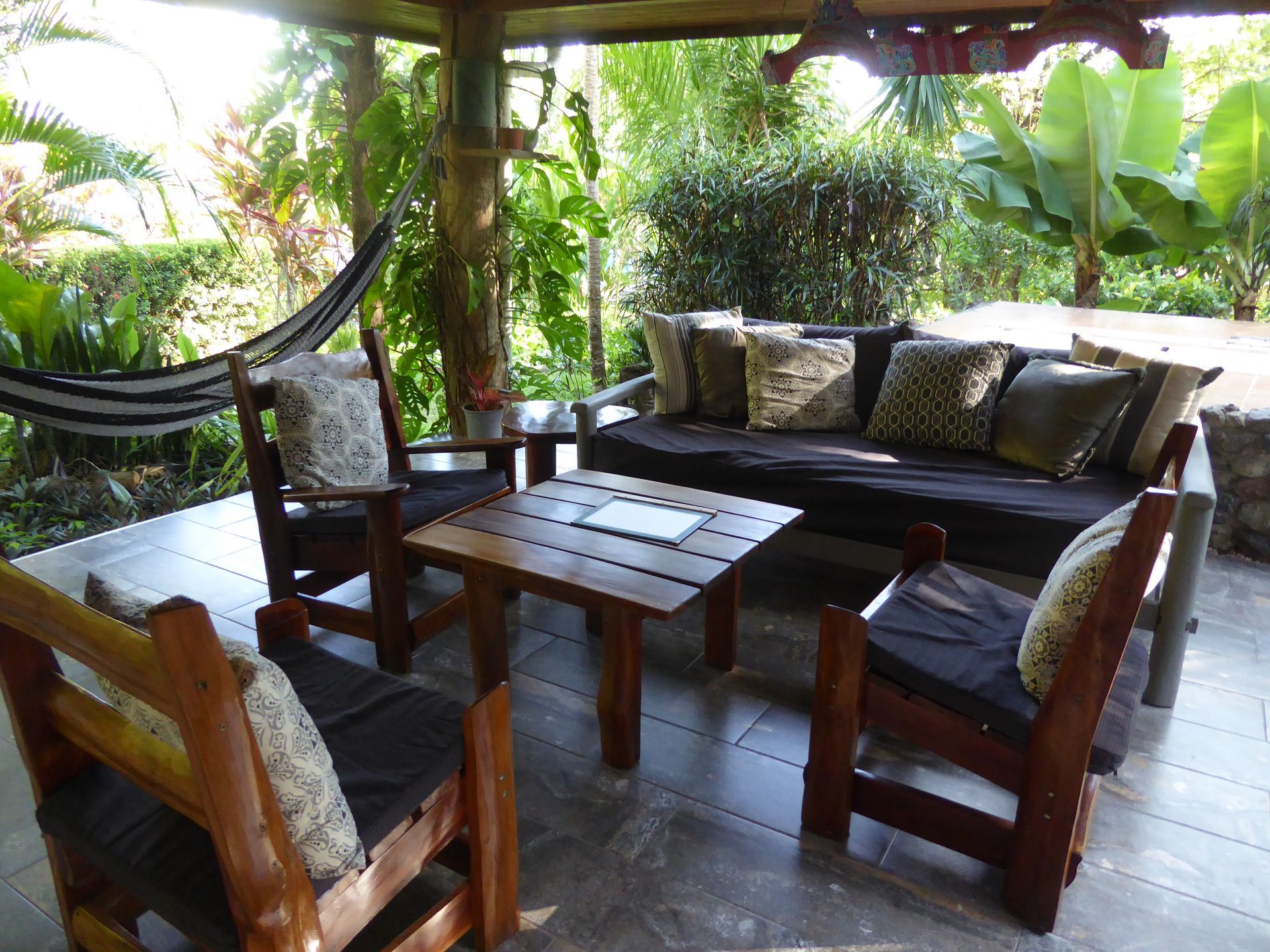 A patio with a couch and chairs and a hammock