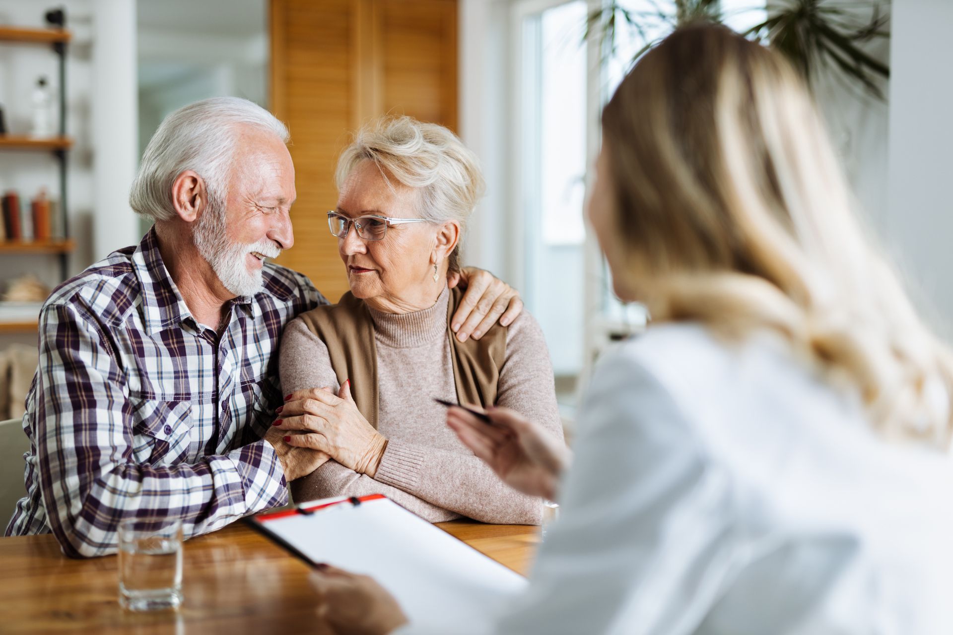 An older couple dances happily in a bright kitchen. The woman is smiling.