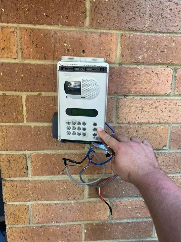 A Person Is Pointing at A Keypad on A Brick Wall — Fortress Locksmiths & Security in Lennox Head, NSW