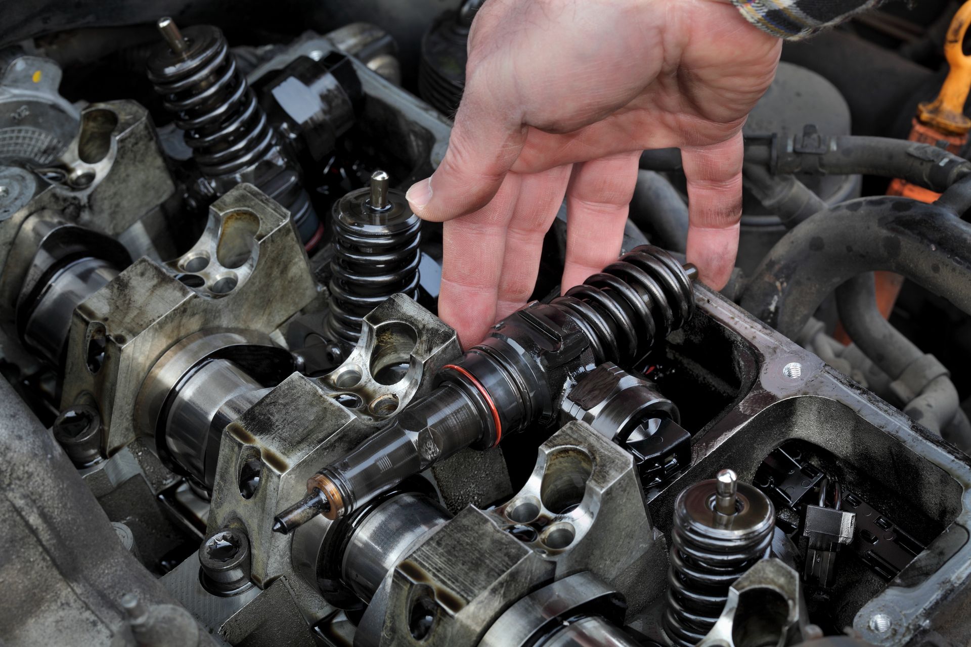 Close-up of a mechanic's hand removing injectors from the cylinder head.