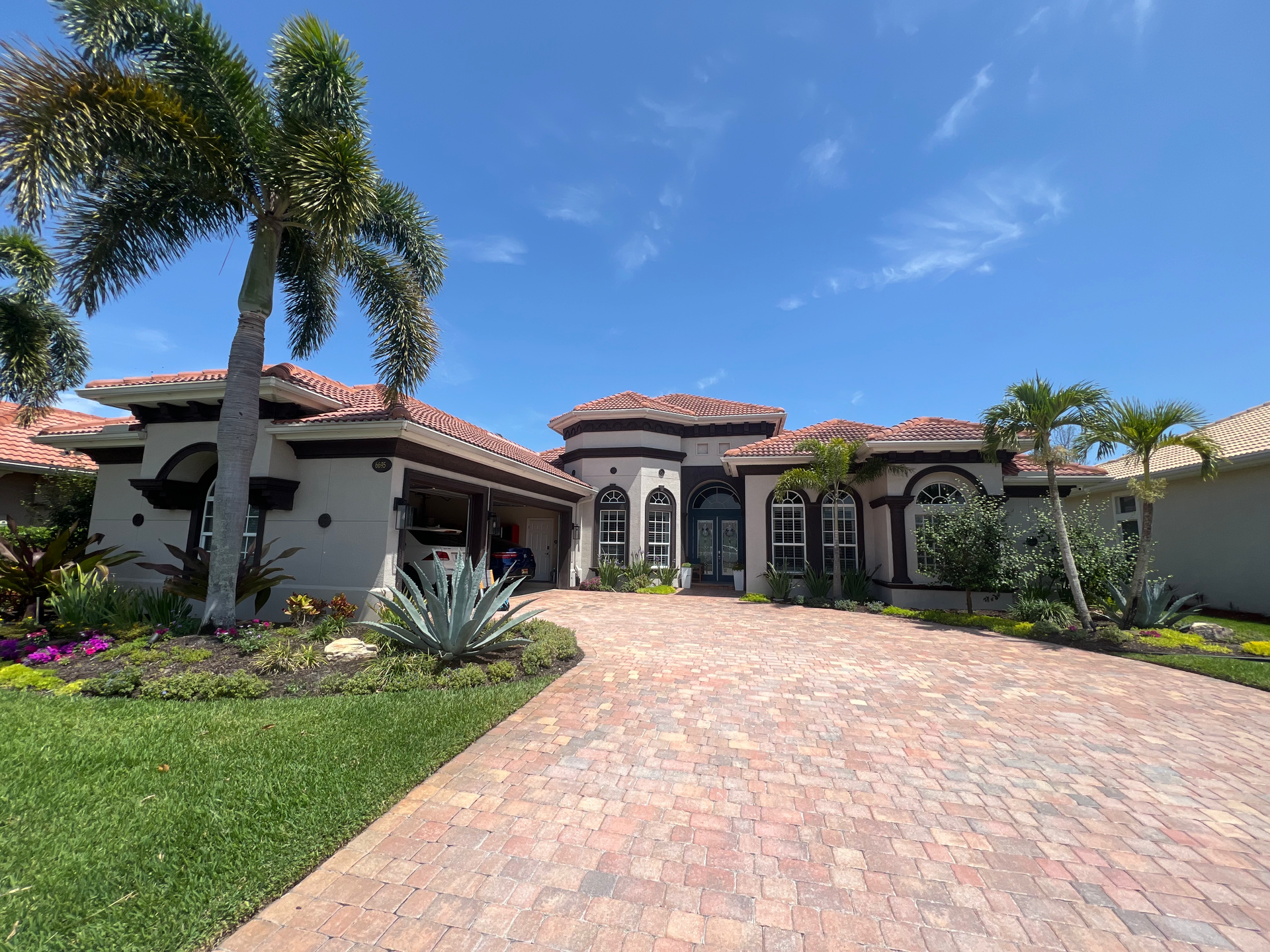 Florida home red roof, long driveway, and blue clear sky.