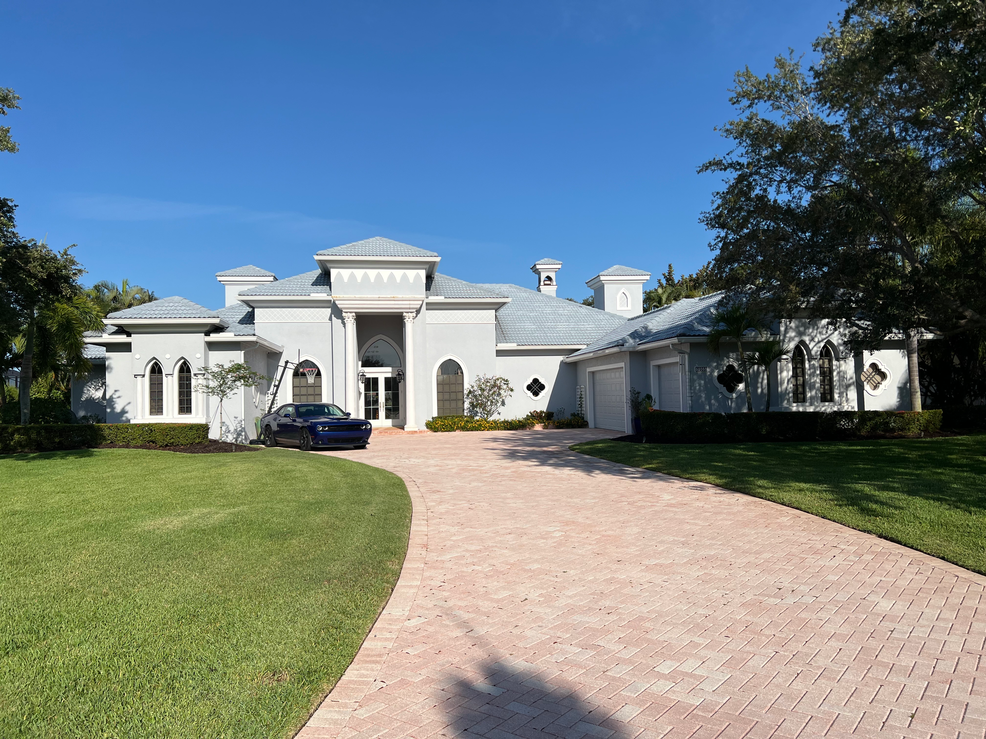 Gray home with long driveway and a car out front.