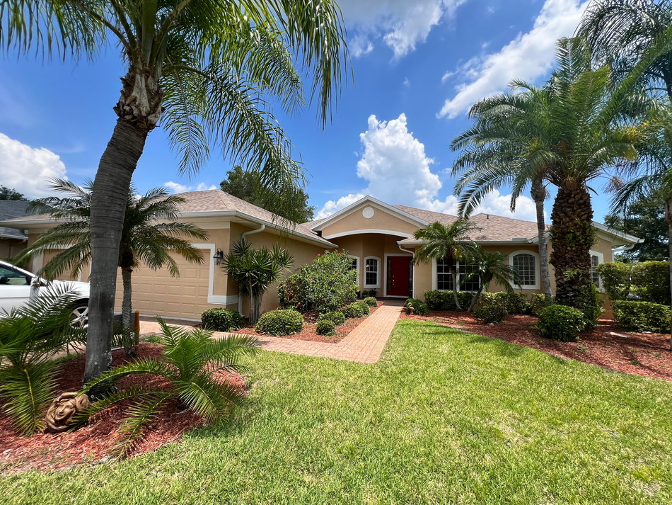 One story home archway over the front door with palm trees, and clouds.