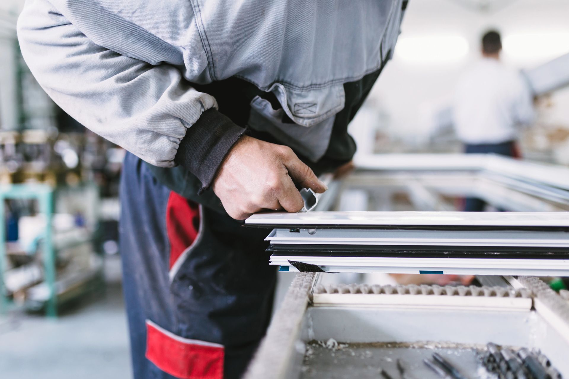 Operaio che assembla il telaio di una finestra in fabbrica.