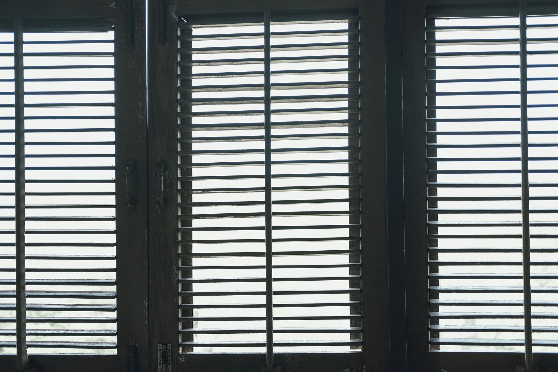 Persiane in legno che bloccano parzialmente la vista attraverso una finestra, stecche orizzontali.