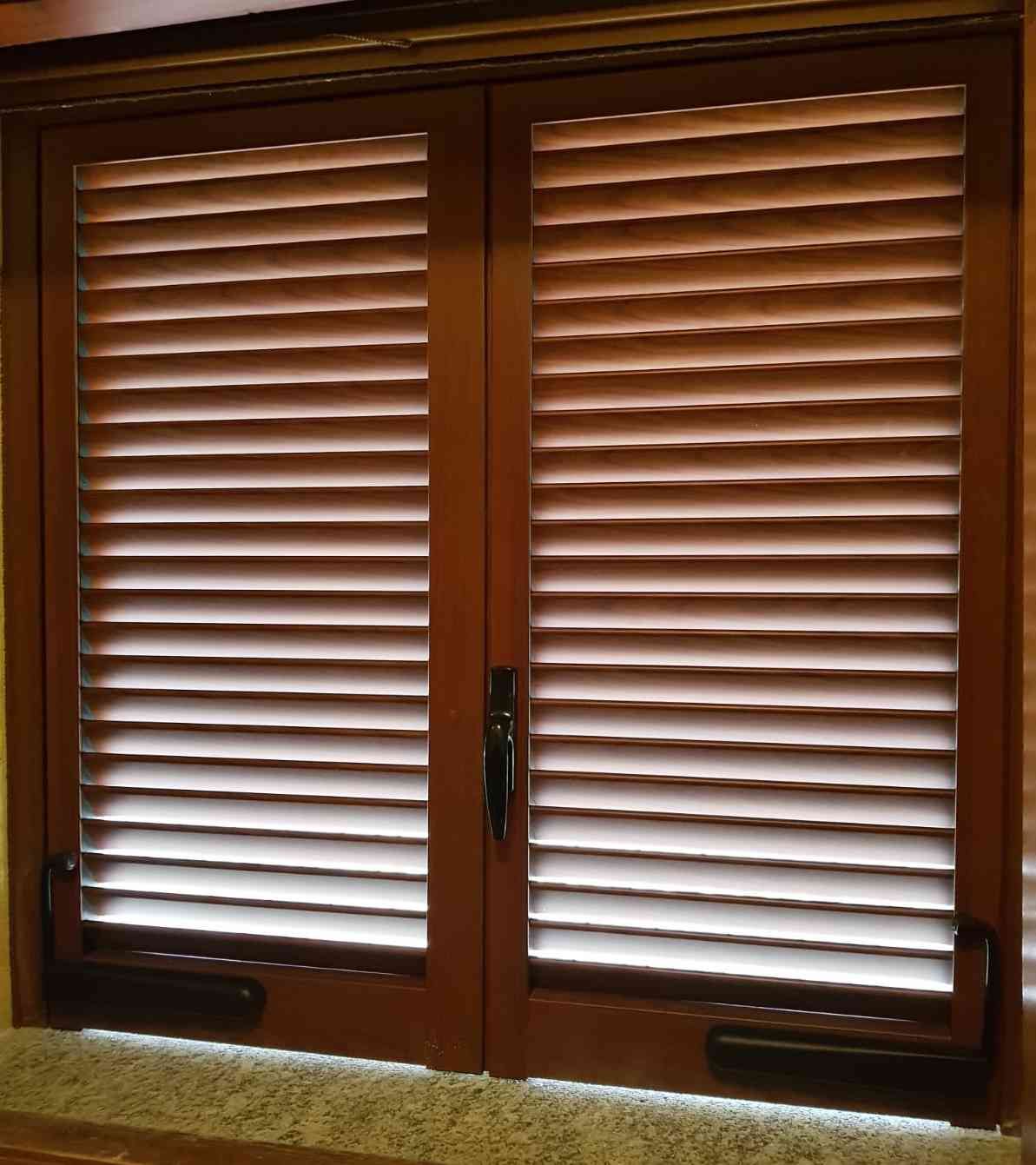 Persiane marroni su una finestra, con la luce che filtra attraverso le stecche.