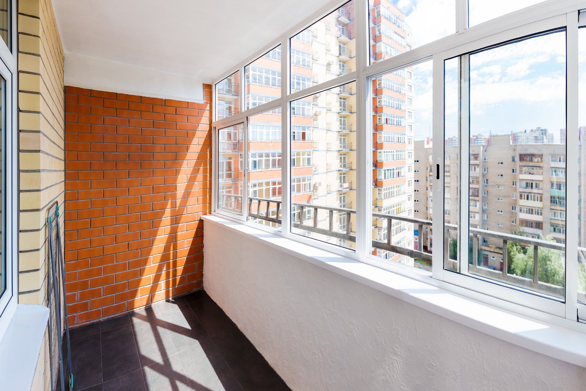 Balcone con finestre a tutta altezza, parete in mattoni rossi e vista sulla città.