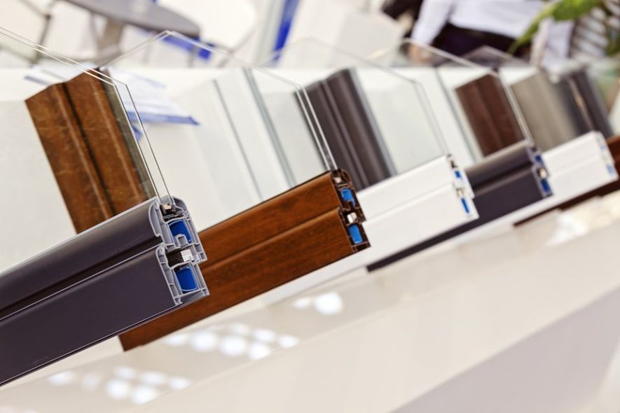 Campioni di telai per finestre in vari colori, esposti su uno scaffale bianco.