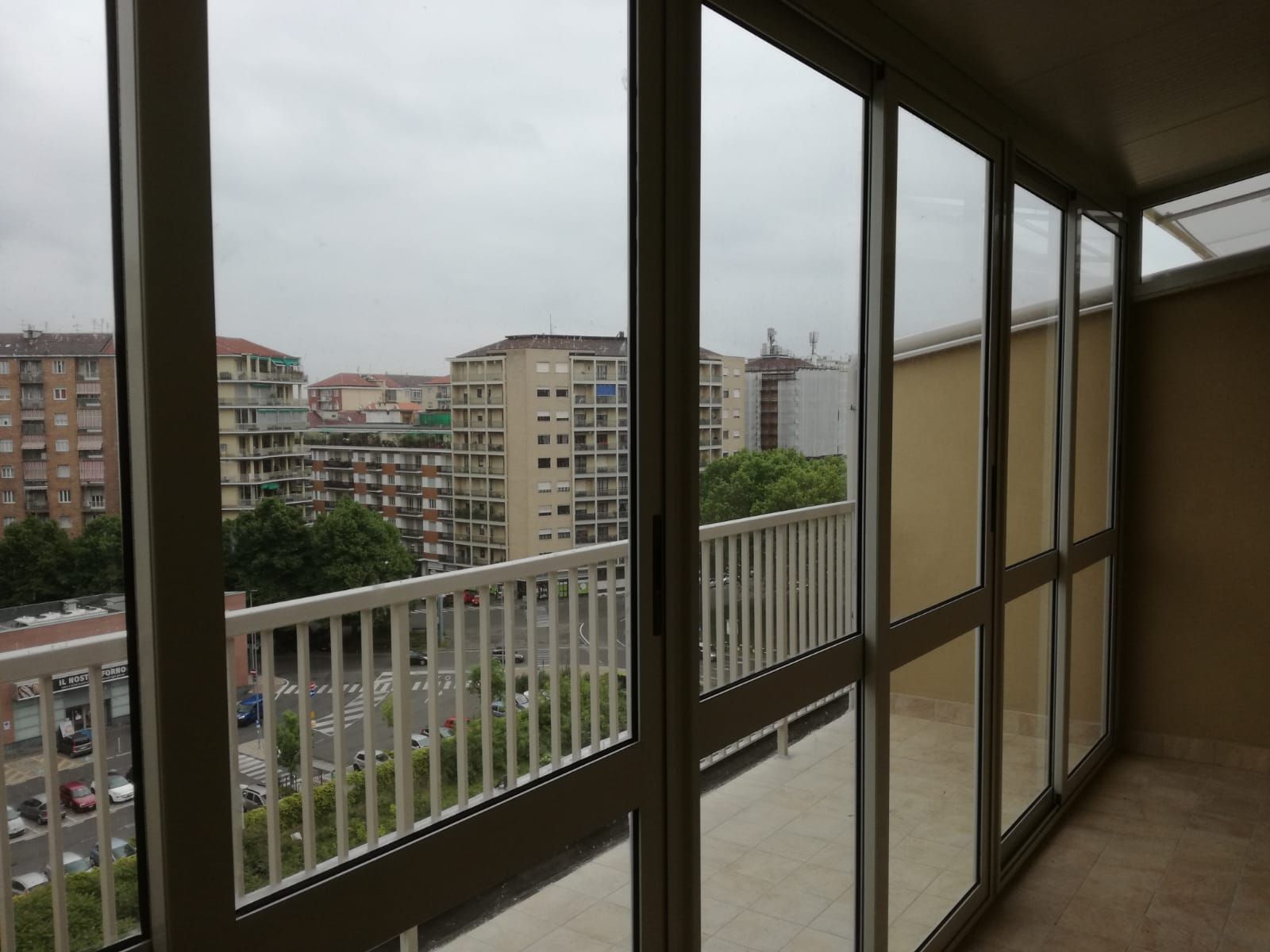 Balcone con vetrate che si affacciano sugli edifici della città in una giornata nuvolosa.