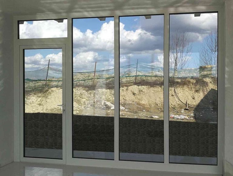 Le finestre e le porte in vetro riflettono il cielo nuvoloso e le costruzioni esterne.