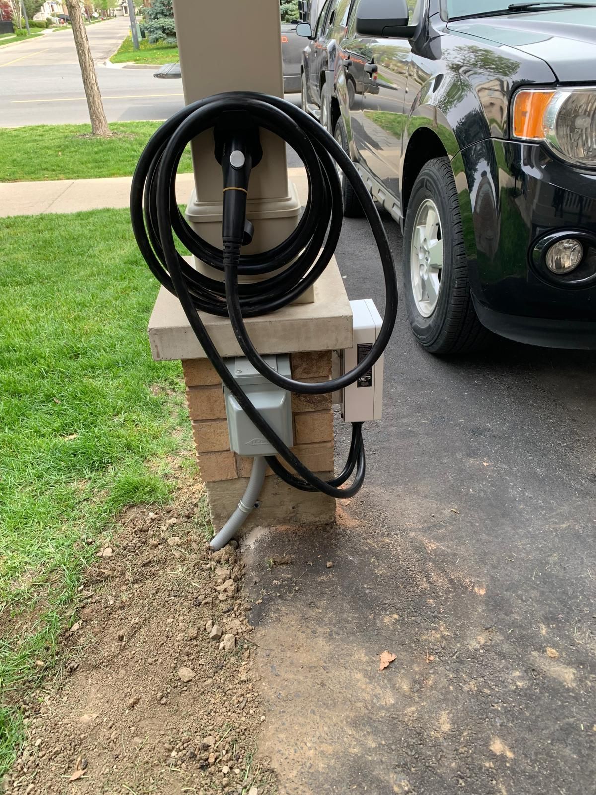 A black suv is parked in front of a charging station.