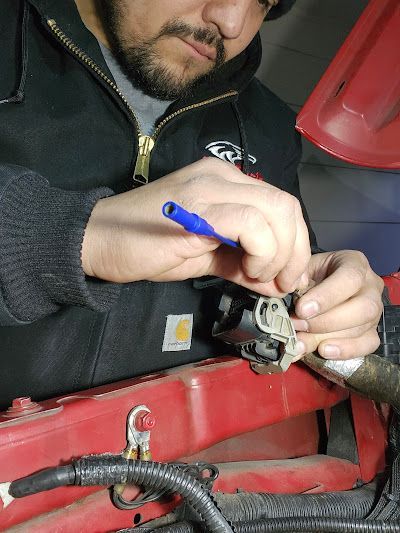A man in a carhartt jacket is working on a red car