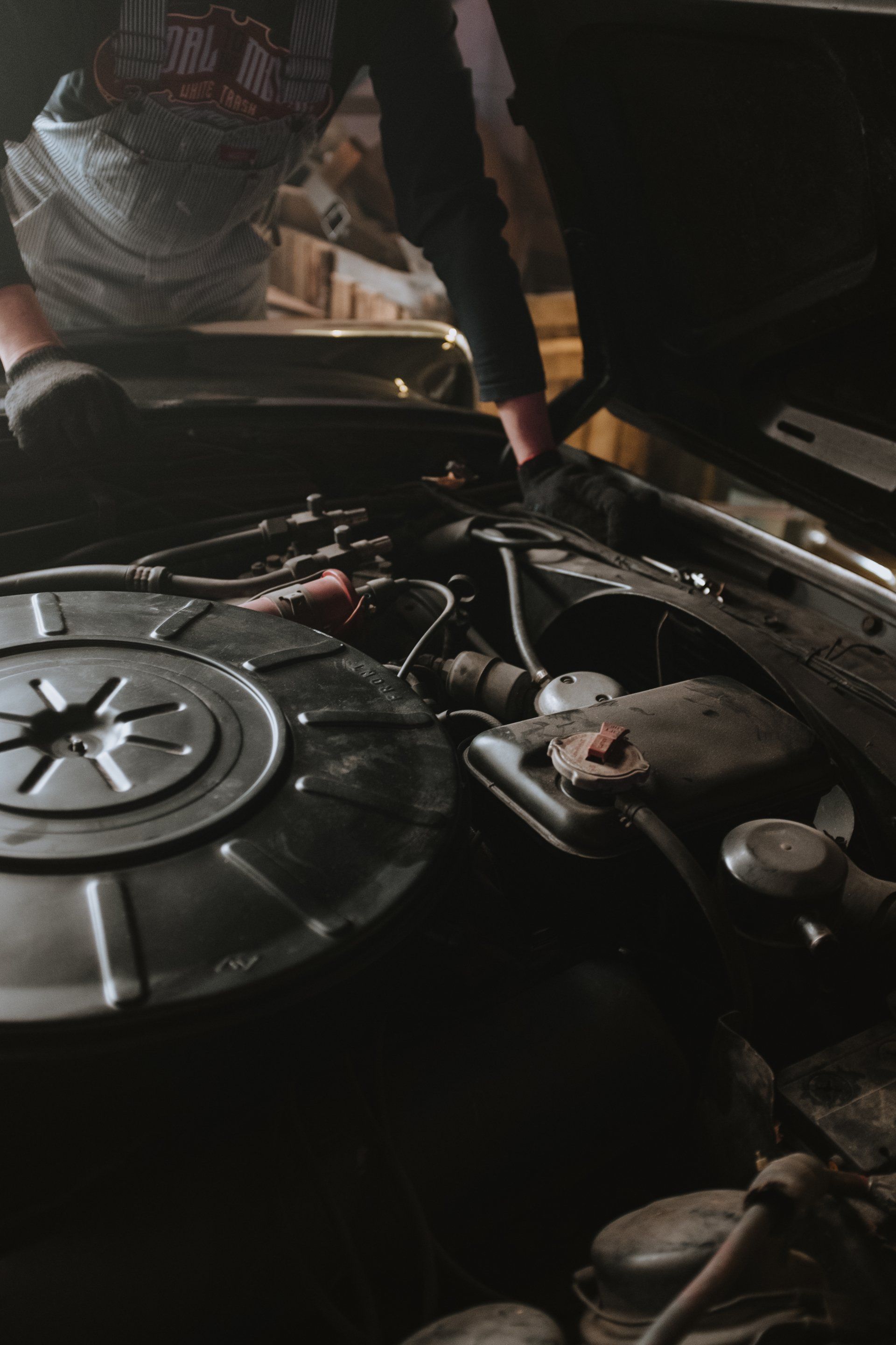 A man is looking under the hood of a car.