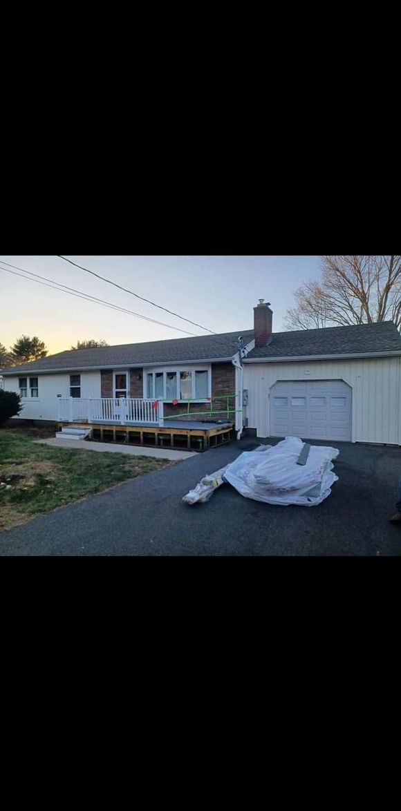 A white house with a garage and a deck in front of it.