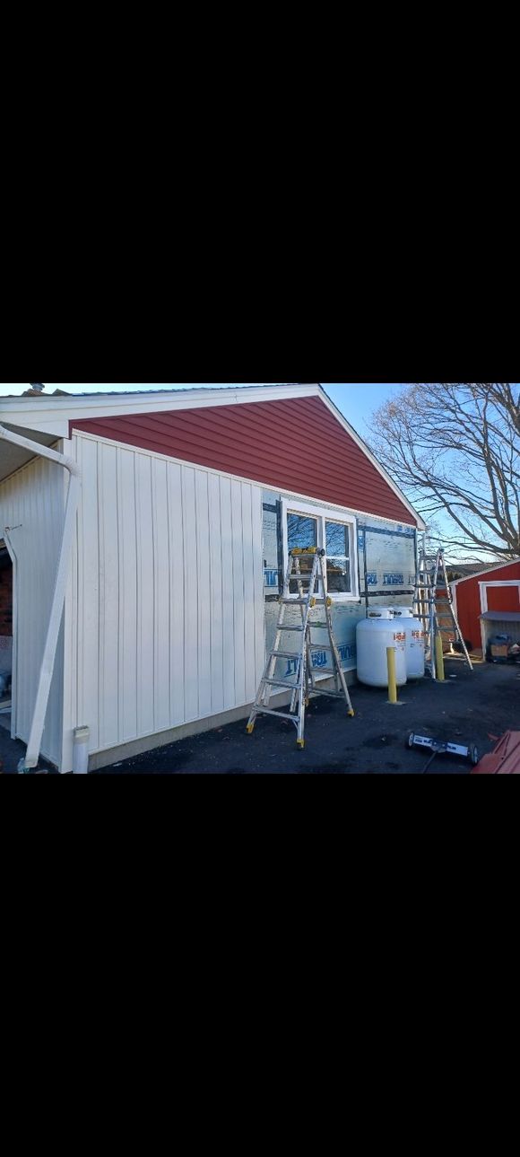 A white house with a red roof is being painted.