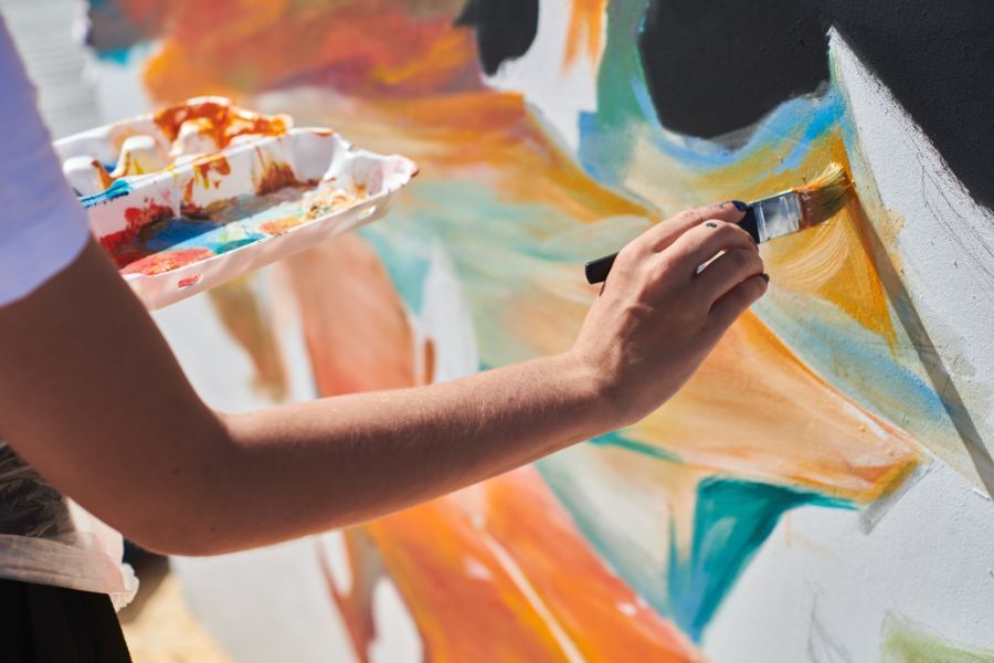 A person is painting a picture on a wall with a brush.