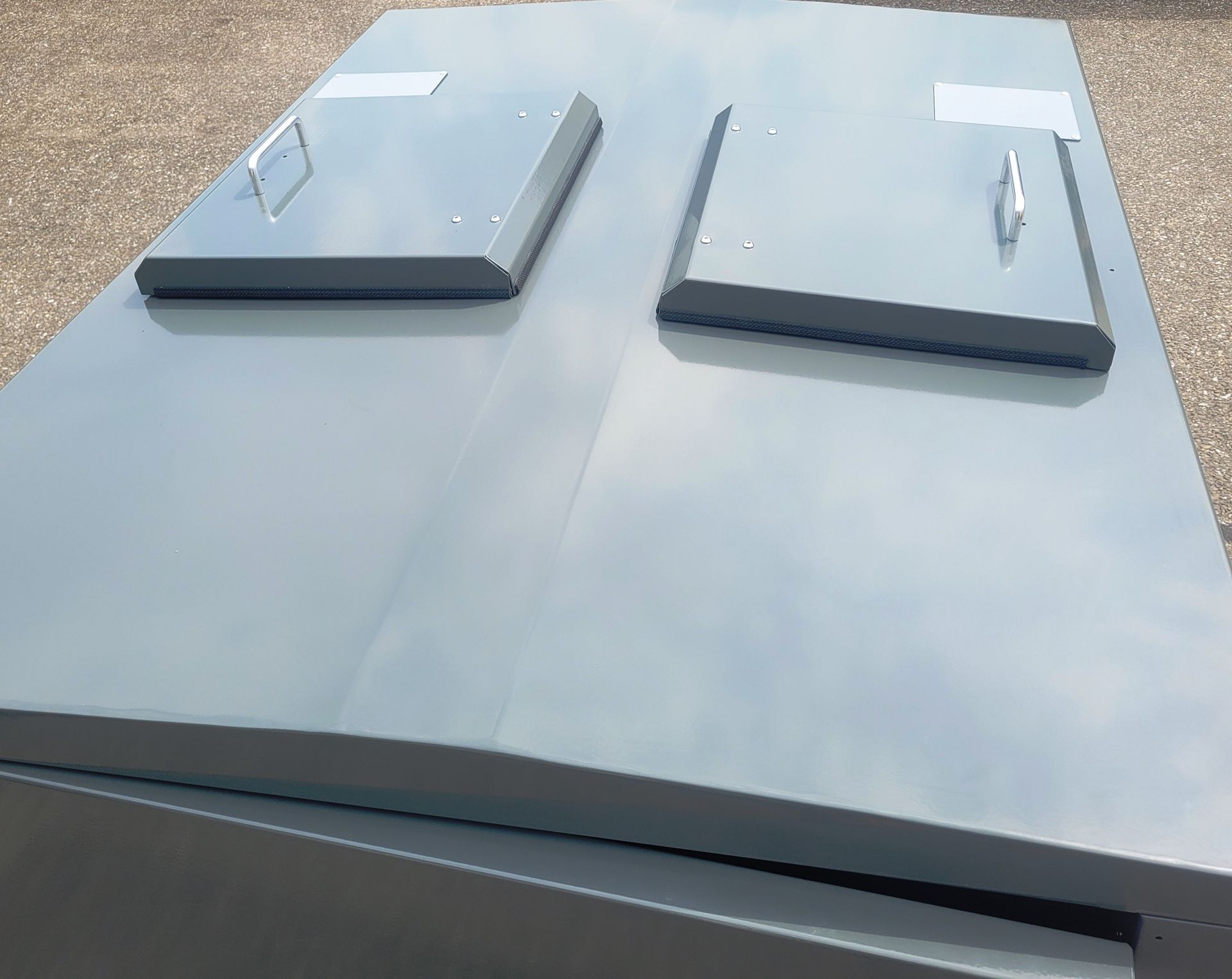 Une boîte utilitaire en métal gris avec deux compartiments à couvercle articulé sur le dessus.