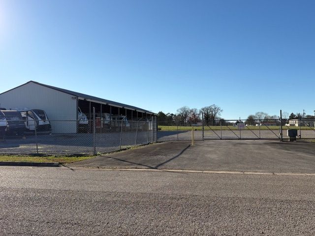 Grey electric car charging at a wall-mounted charging station.