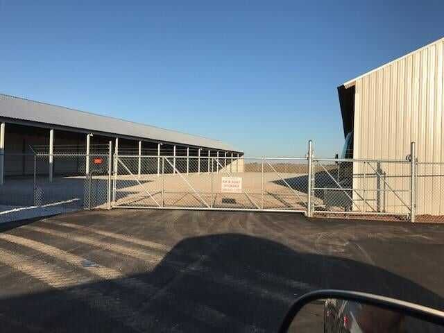Rooftop solar panel installer in orange vest and hard hat working on panels during sunset.