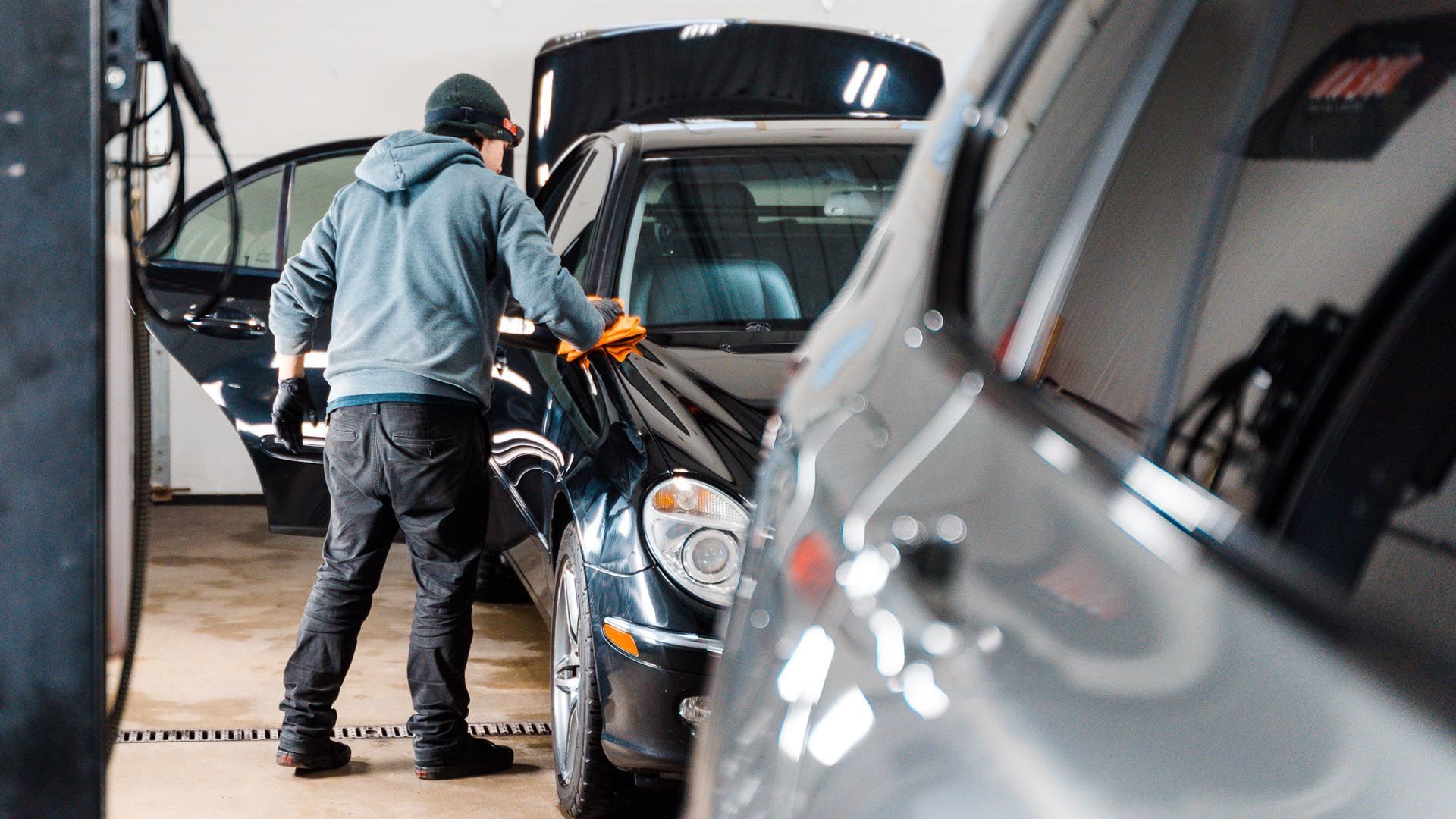 A man is cleaning a car in a garage.