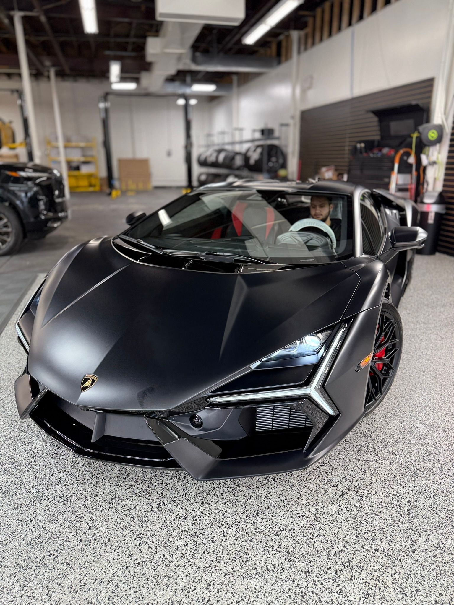 A black lamborghini aventador is parked in a garage.