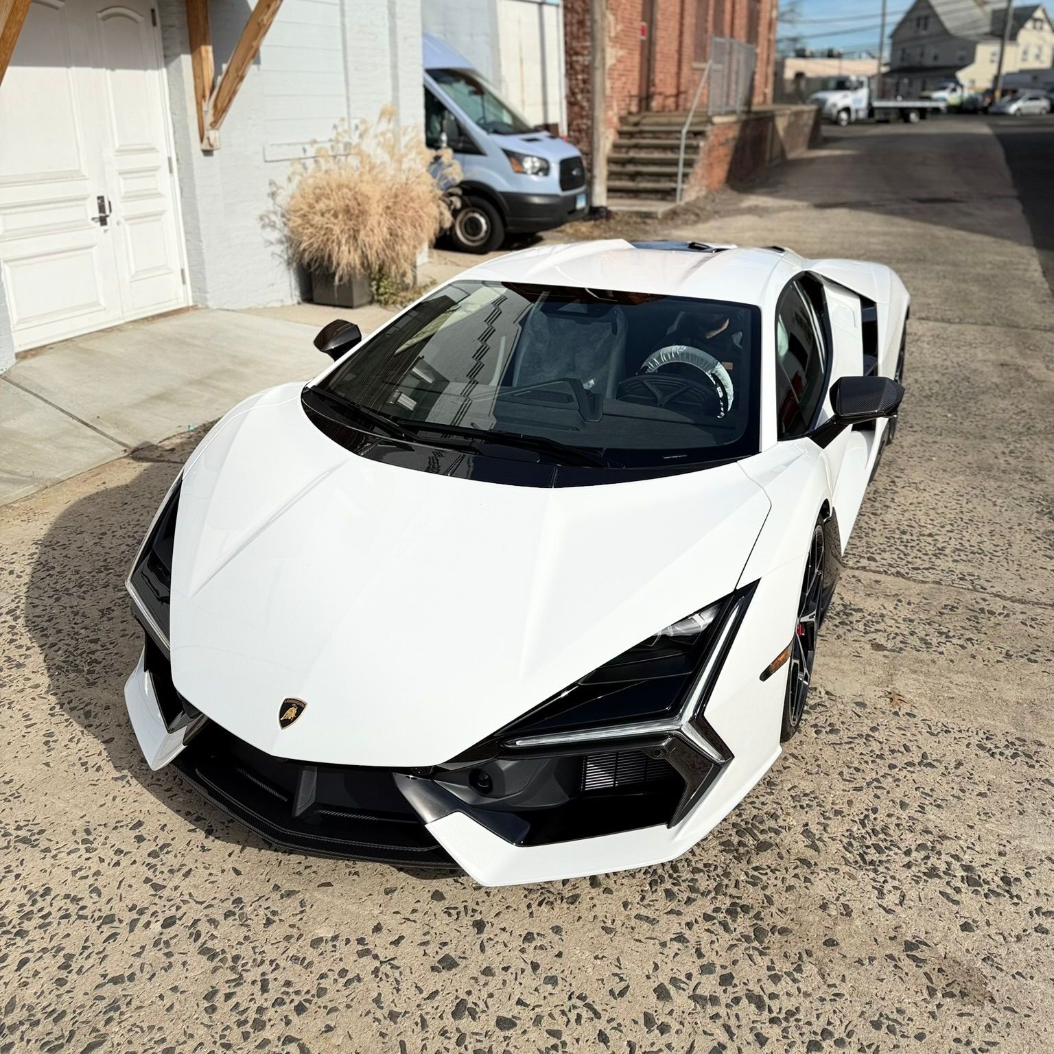 A white lamborghini aventador is parked in front of a building.