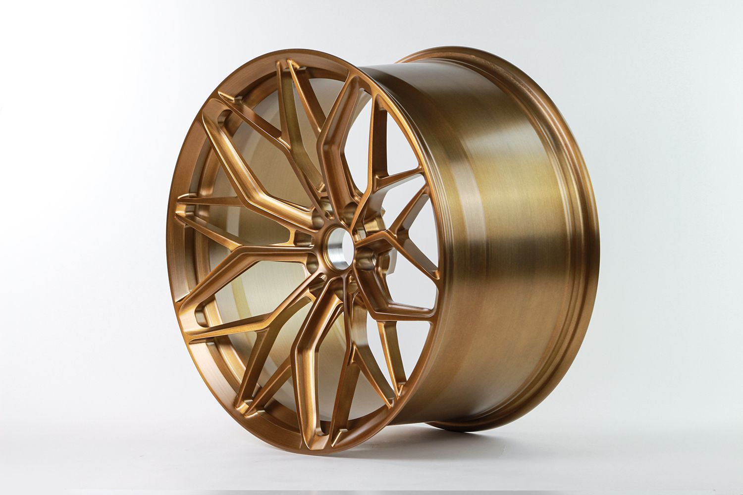 Bronze-colored alloy car wheel with a multi-spoke design against a white background.
