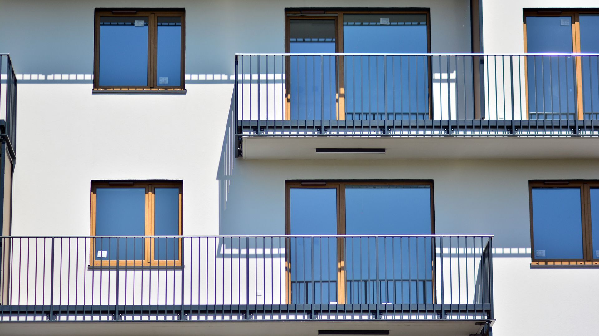 A white apartment building with blue windows and balconies.