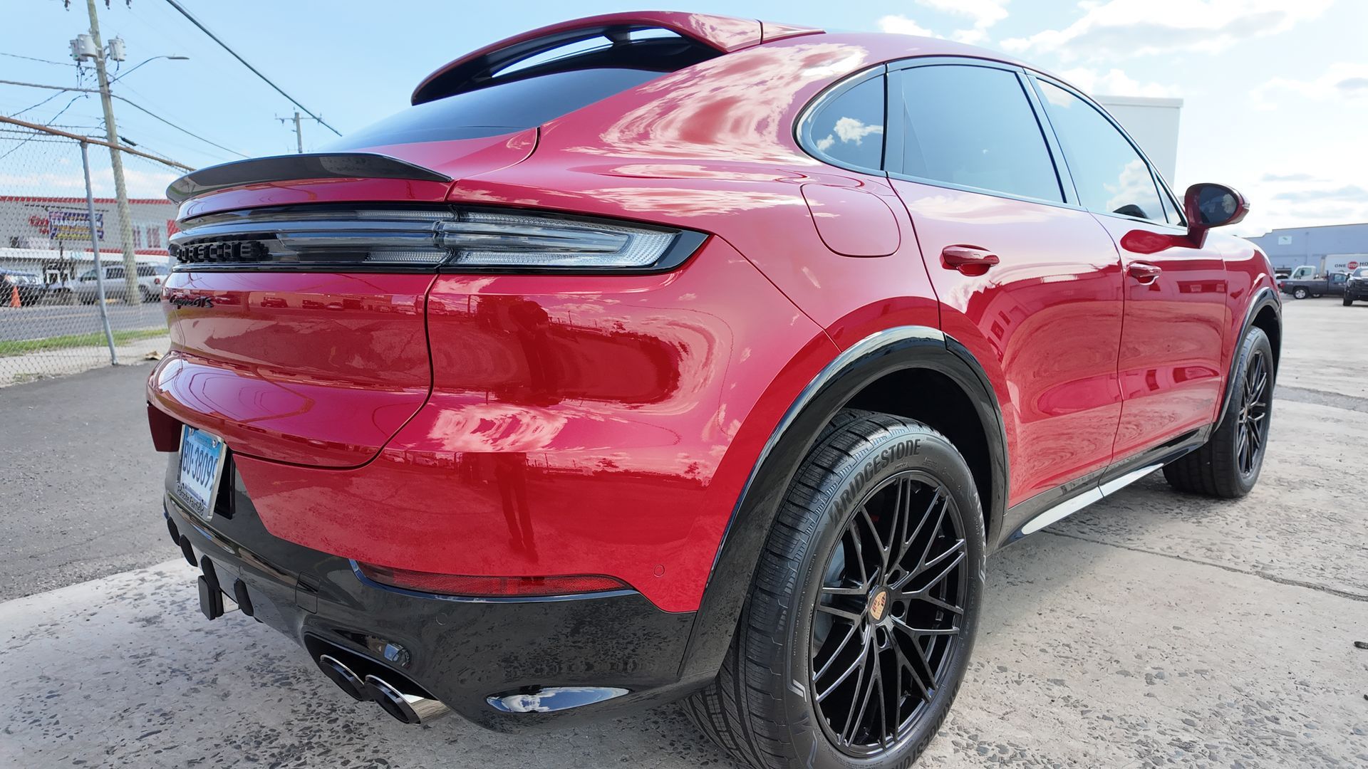 Red Porsche SUV, black wheels, rear view, outdoors.