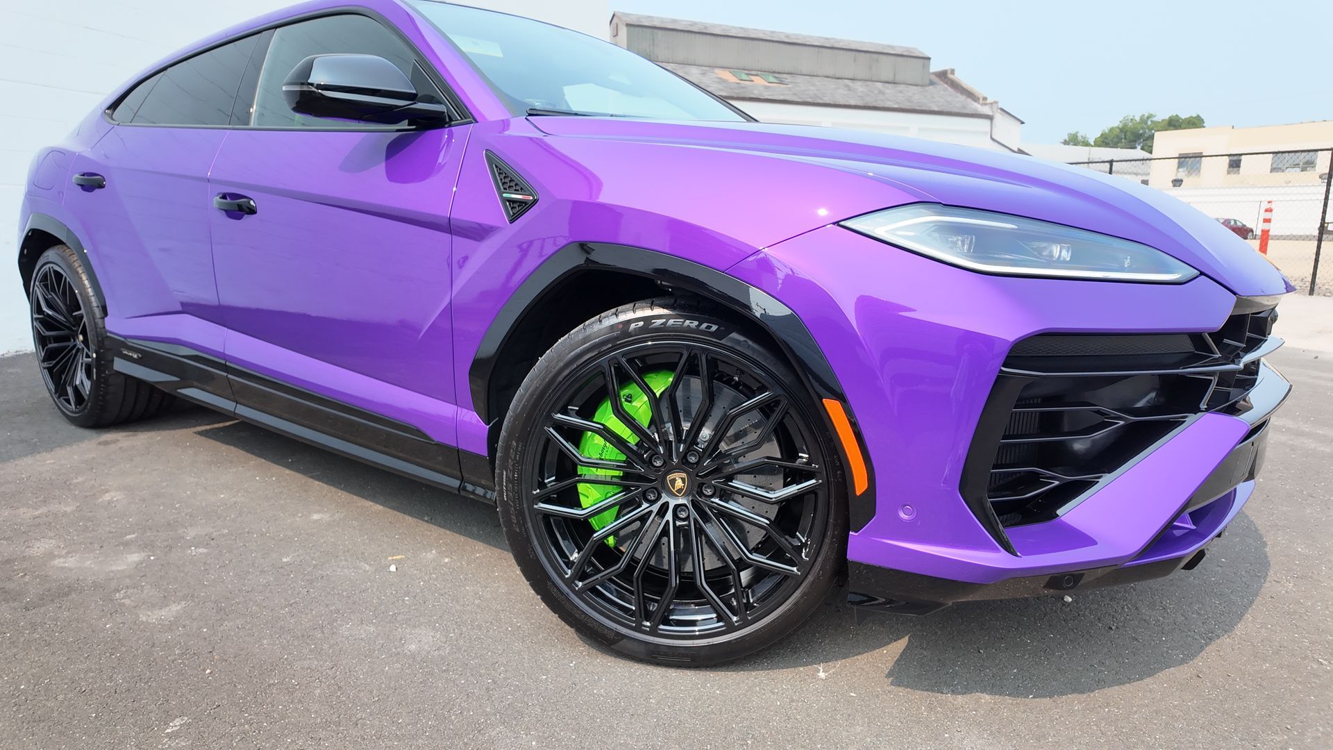Purple Lamborghini SUV with black wheels and lime green brake calipers.