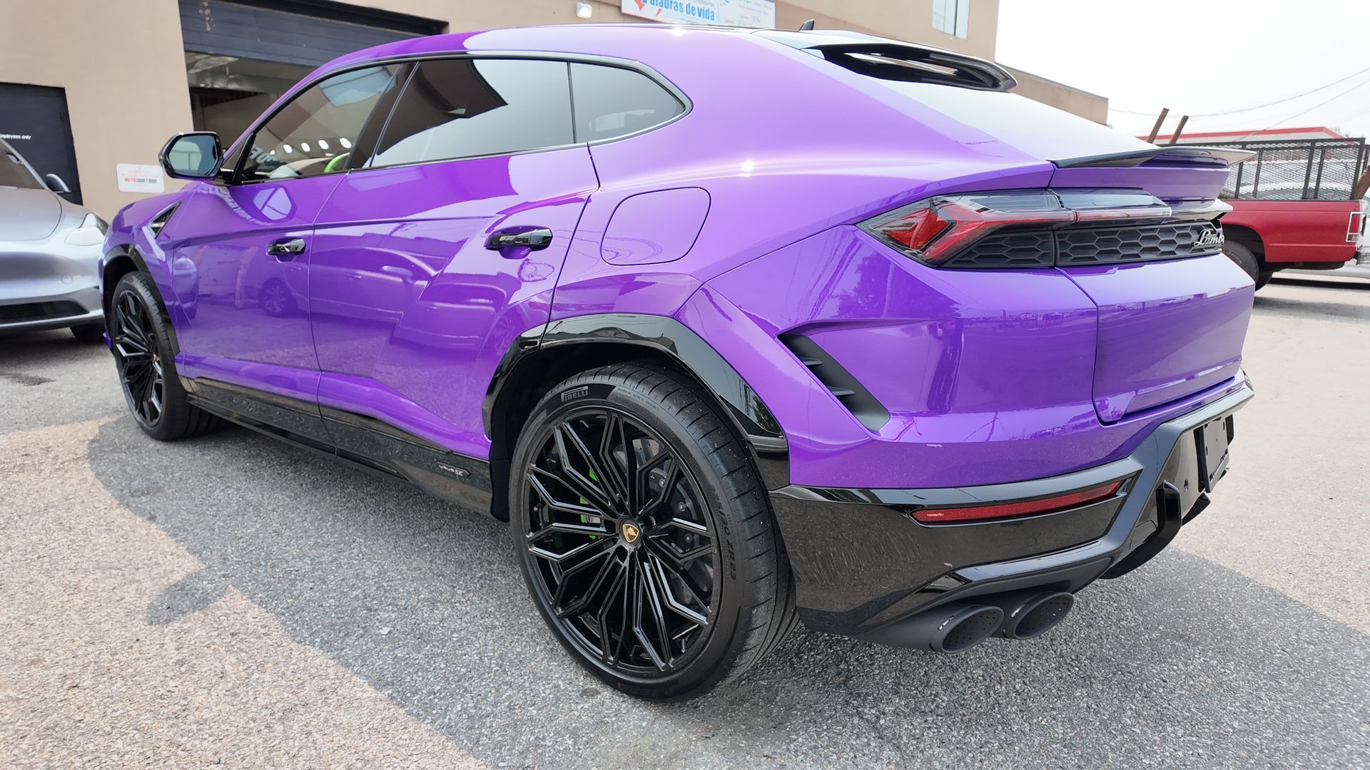 Purple Lamborghini Urus SUV with black wheels parked outside.