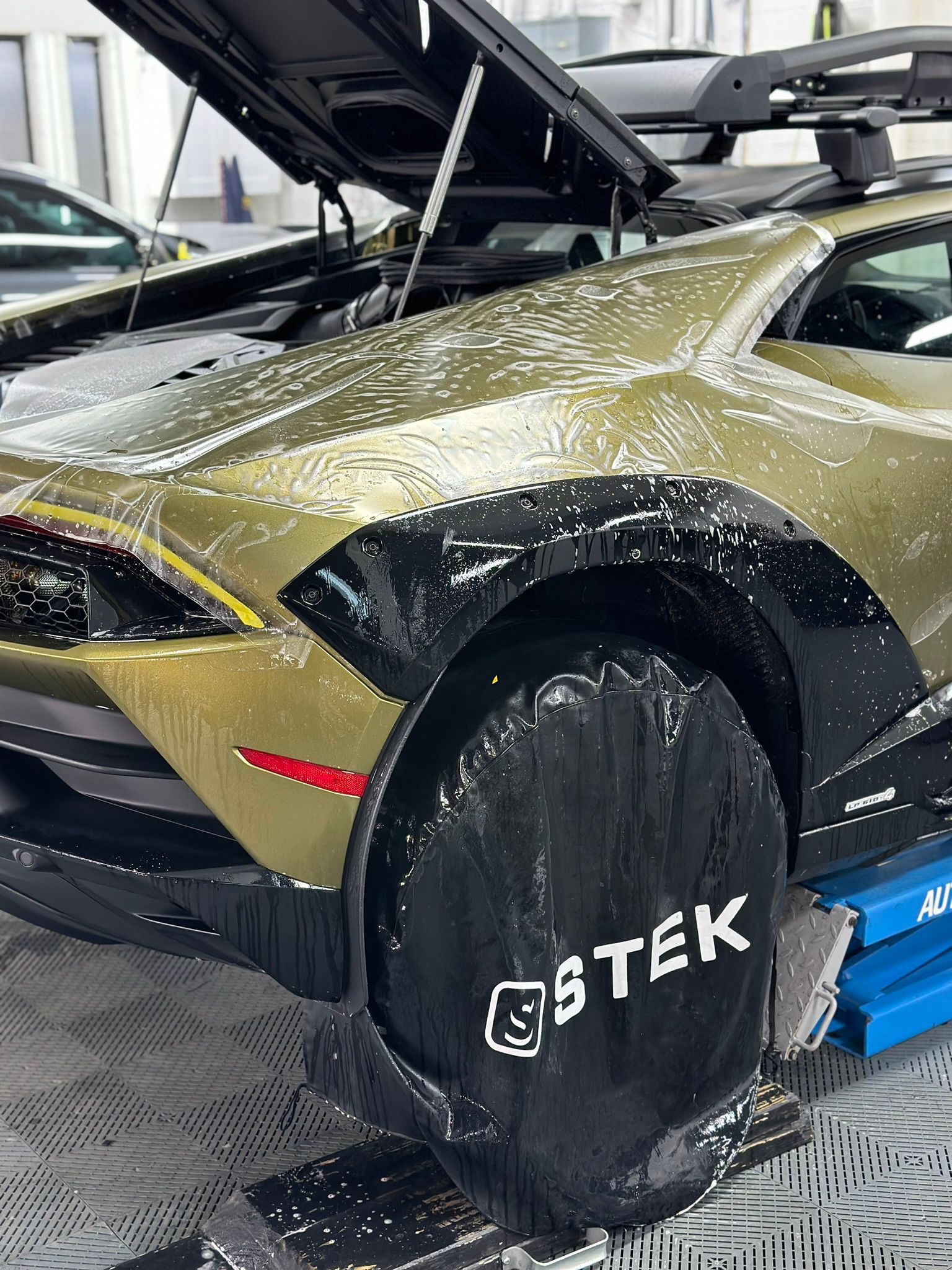 Gold Lamborghini with black accents, covered in soap suds.