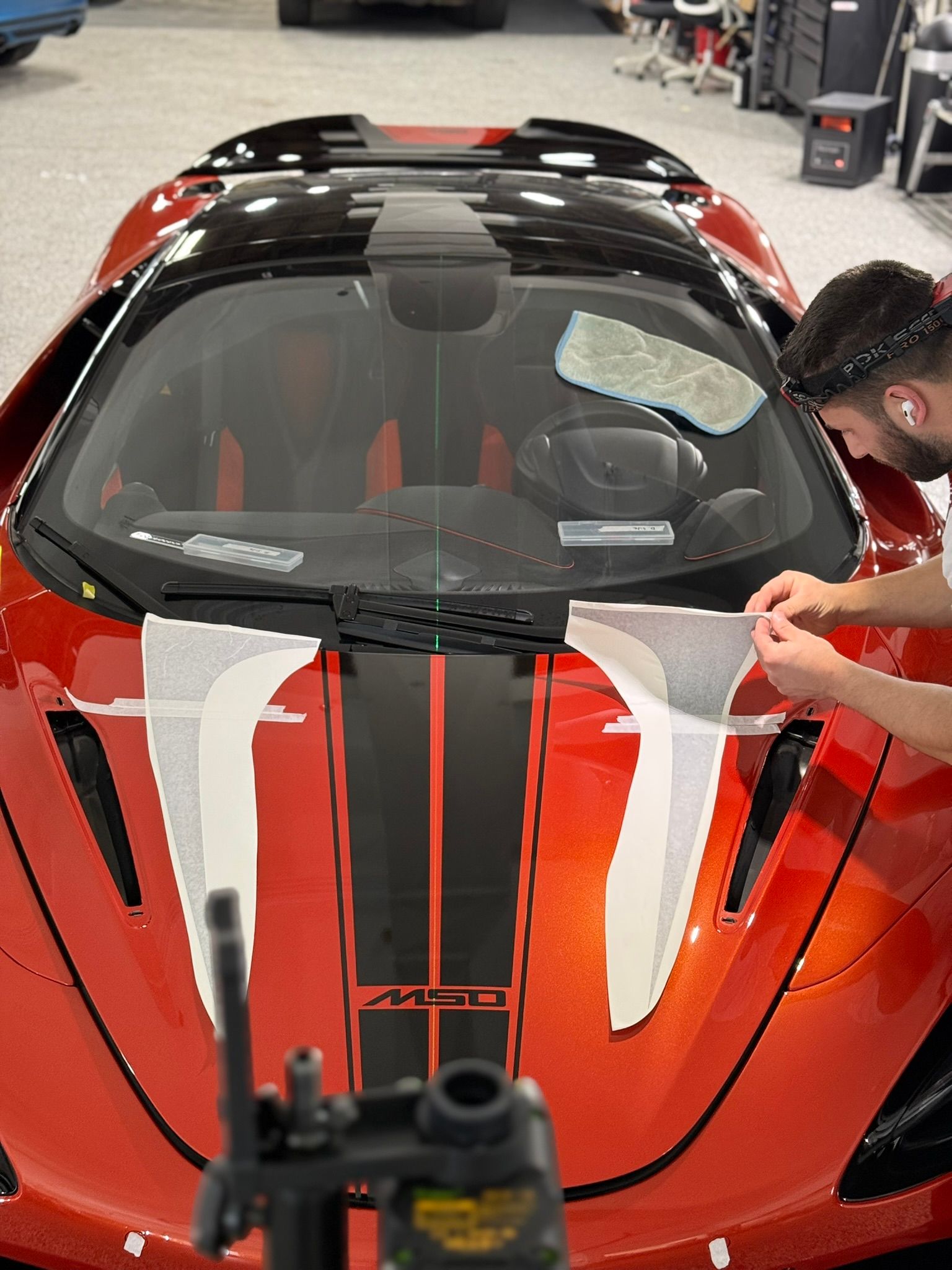 A man is working on a red sports car in a garage.