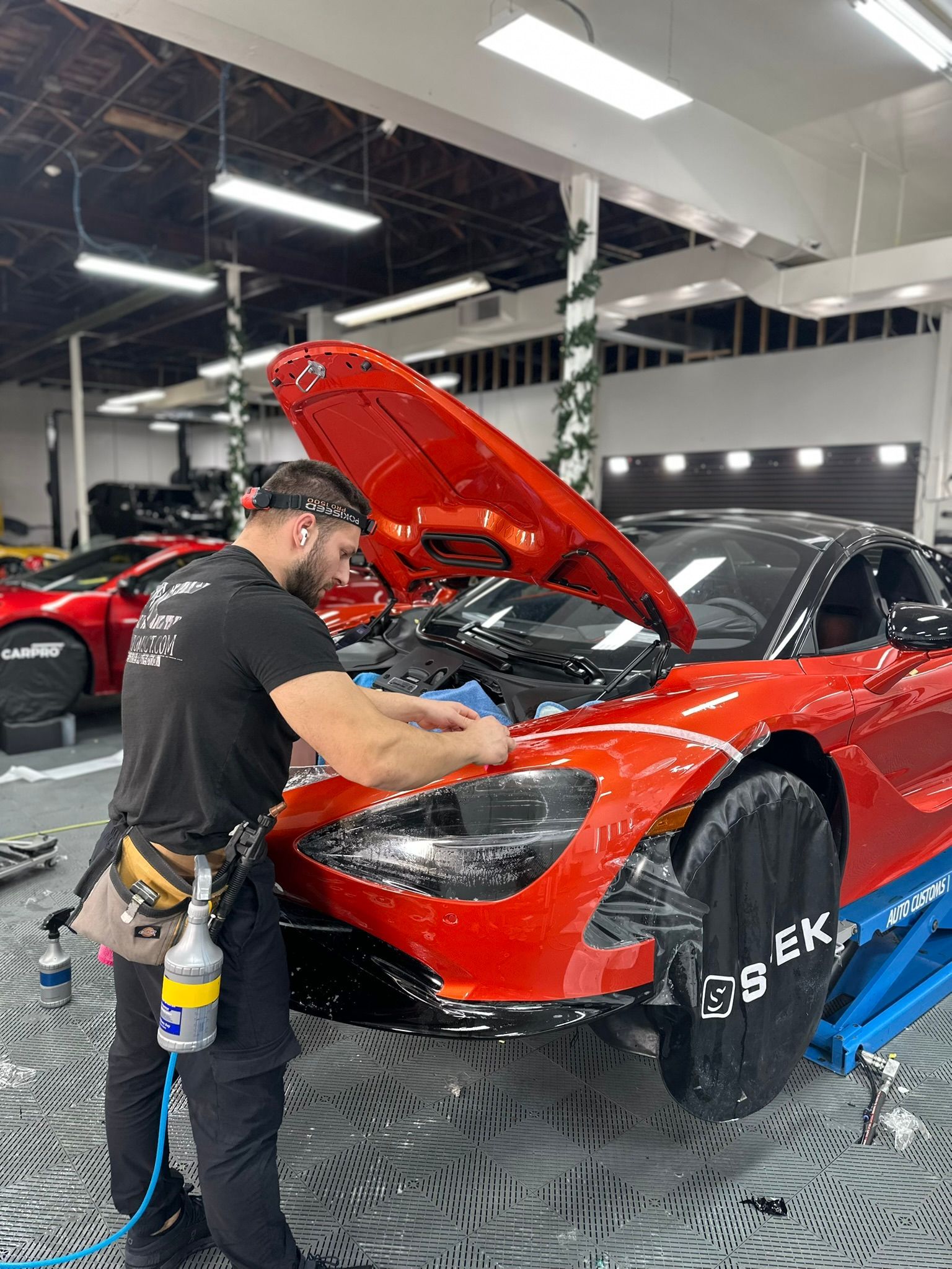 A man is working on a red sports car in a garage.