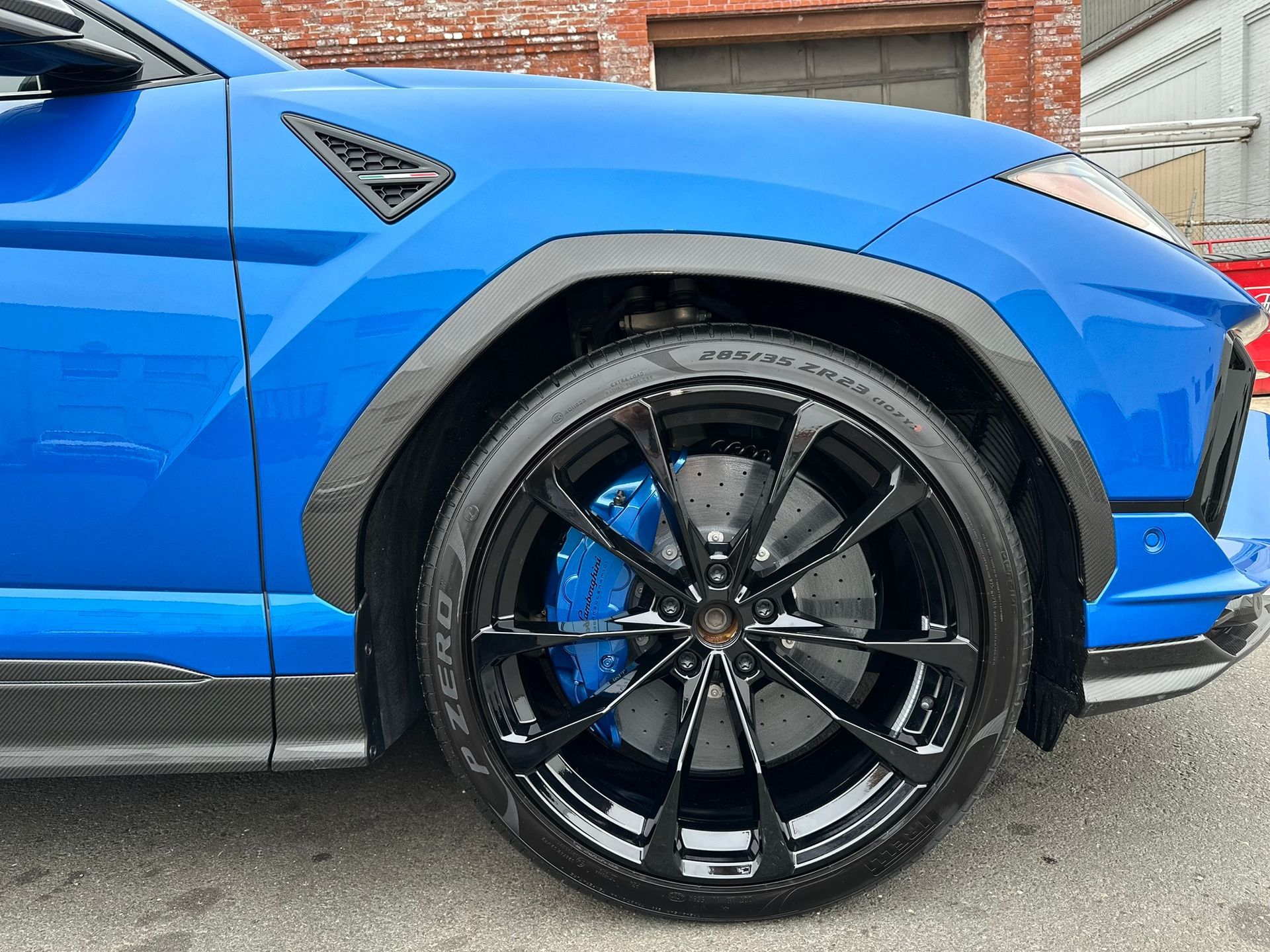 Blue Lamborghini Urus SUV with black rims and blue brake calipers.