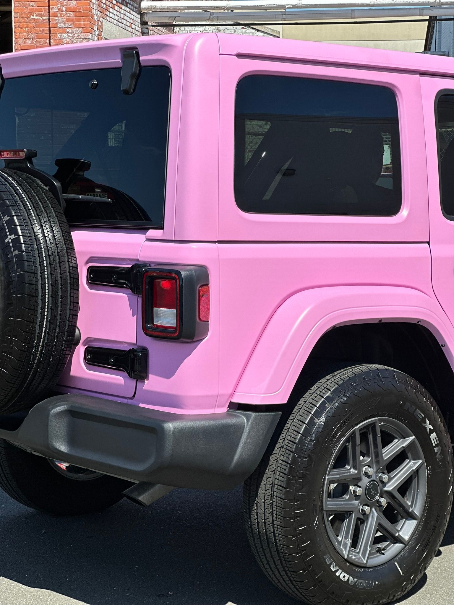 A pink jeep is parked on the side of the road.