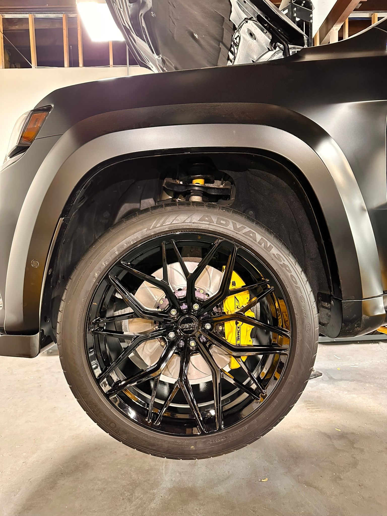Black car wheel with yellow brake calipers, black rim, and black fender.