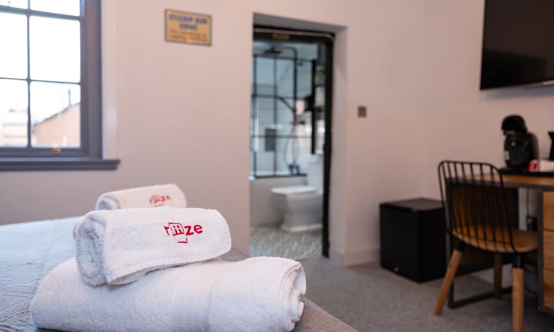 A hotel room with a bed , chair , desk and television.