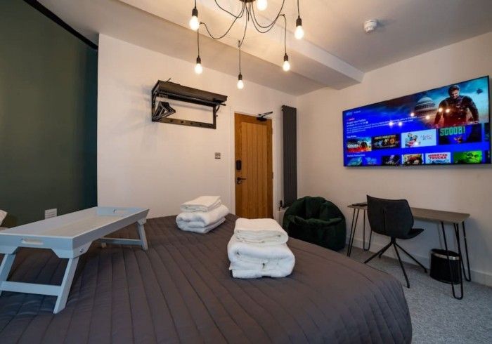 A bedroom with a large flat screen tv on the wall above the bed.