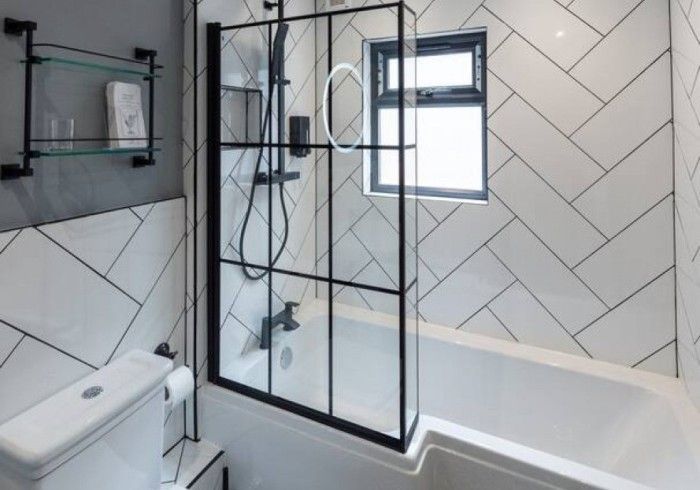 A bathroom with a bathtub , toilet , shower and window.