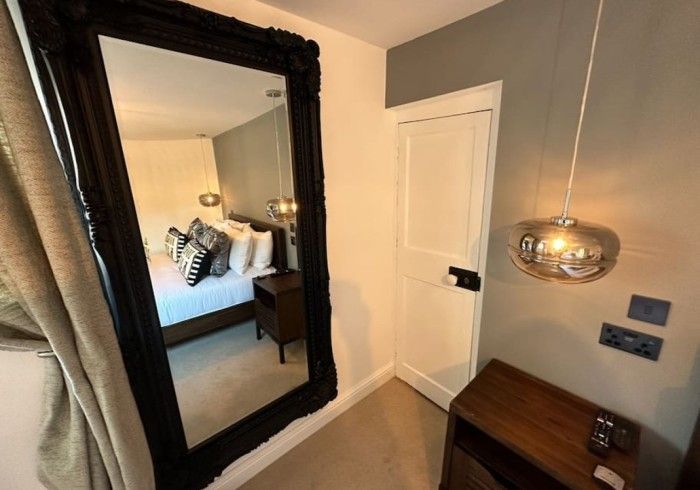 A bedroom with a large mirror and a bed.