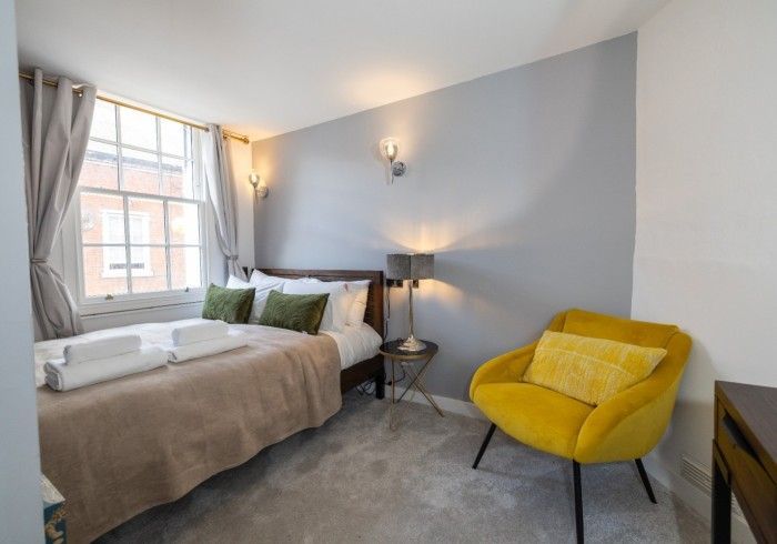 A bedroom with a bed and a yellow chair