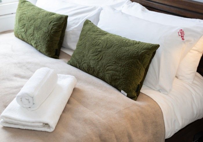 A bed with green pillows and white towels on it