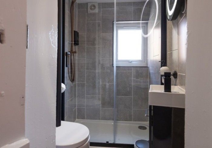 A bathroom with a toilet , sink and shower.