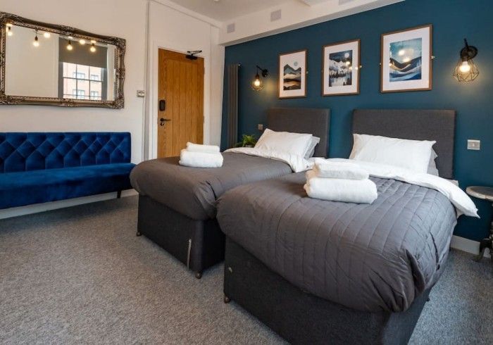 A hotel room with two beds and a blue couch