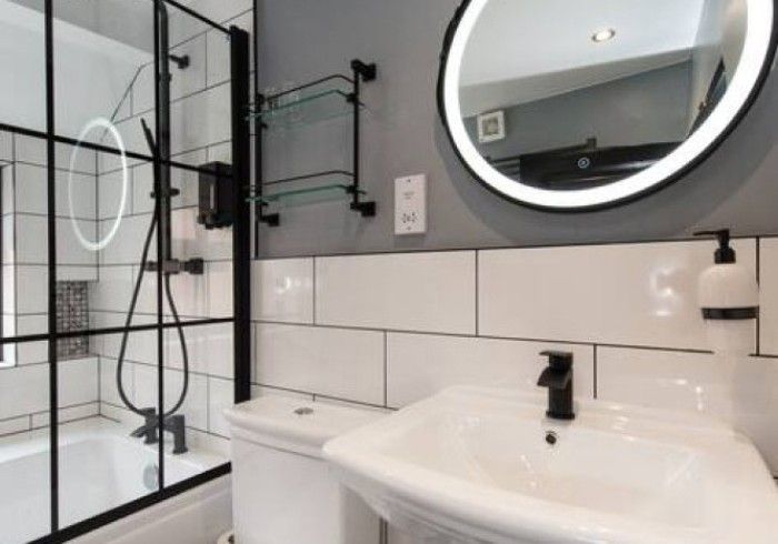 A bathroom with a sink , toilet , shower and mirror.