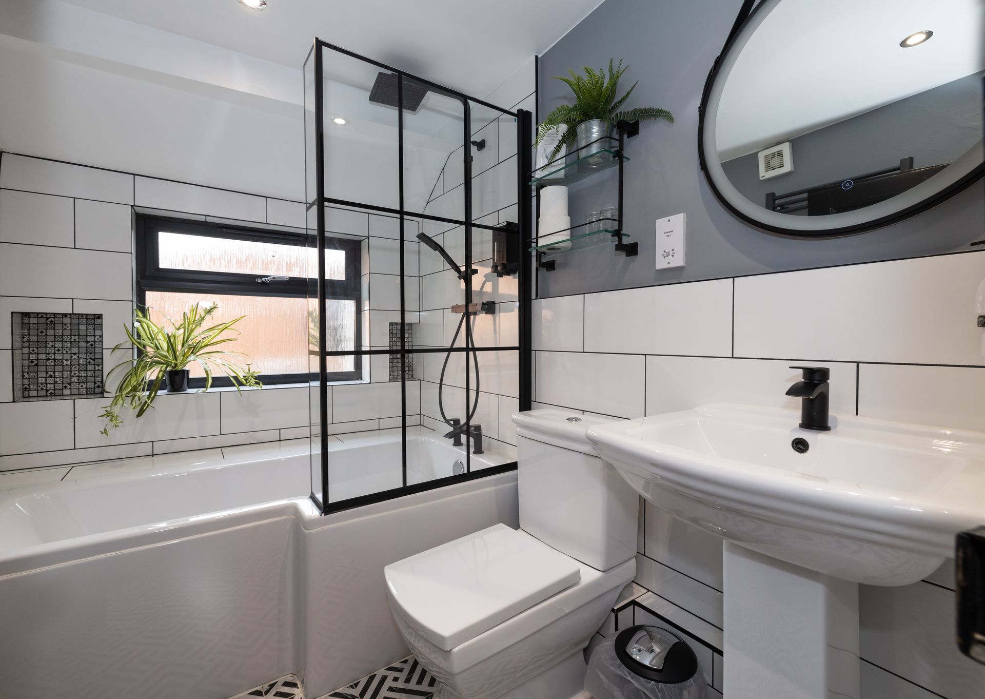 A bathroom with a toilet , sink , tub and mirror.