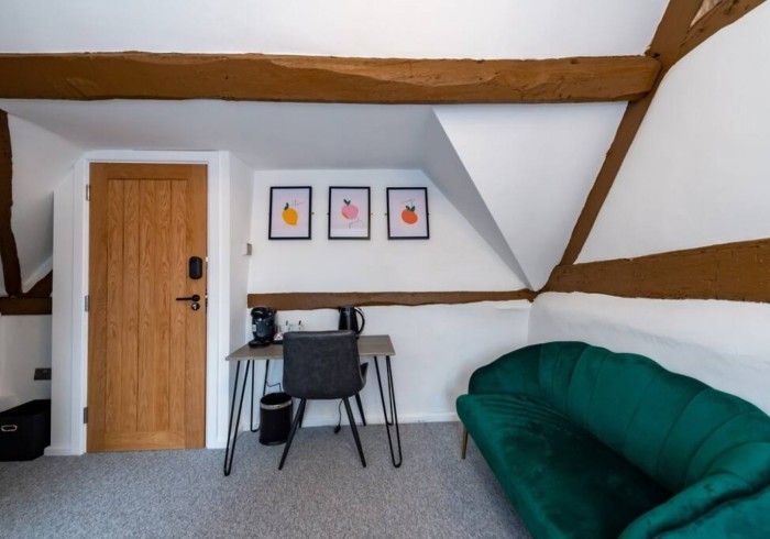 A room with a green couch and a desk