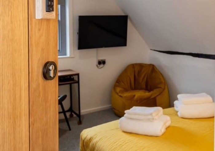 A bedroom with a yellow bean bag chair and a flat screen tv